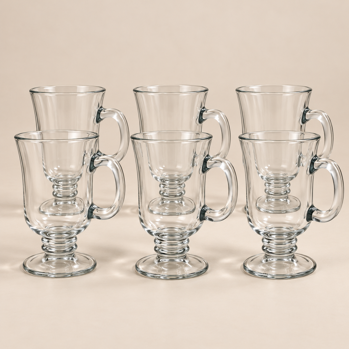 Six Clara 250 ml footed glass cups on a light beige studio background