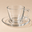 Clear glass coffee cup and saucer on beige studio background