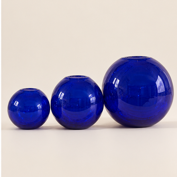 Studio photo of three cobalt blue spherical glass vases in small, medium and large sizes