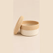 Handmade two-tone woven basket with lid on light beige studio background