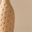 Cream dimpled pottery vase on light beige background