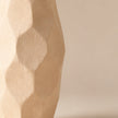 Ivory faceted pottery vase on light beige background