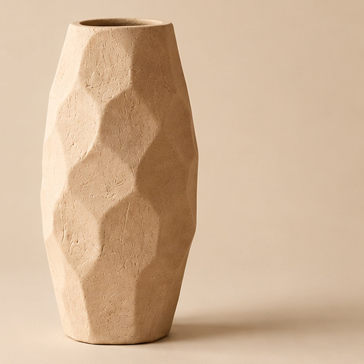 Faceted cream pottery vase on light beige background