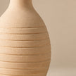 Cream ribbed pottery vase on light beige background